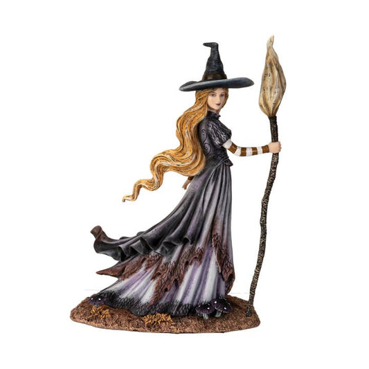 Figurine of a witch with a long black dress and hat, holding a broomstick on a white background