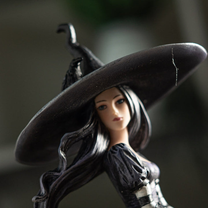 Figurine of a witch with a large black hat on a dark background