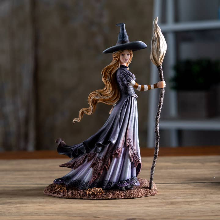 Figurine of a witch with a broom on a wooden surface