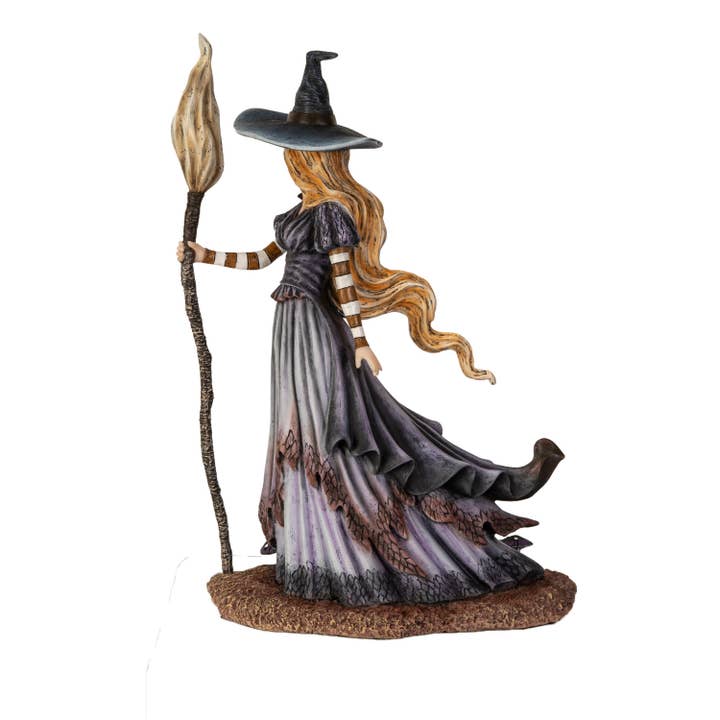 Statue of a witch holding a broomstick on a white background