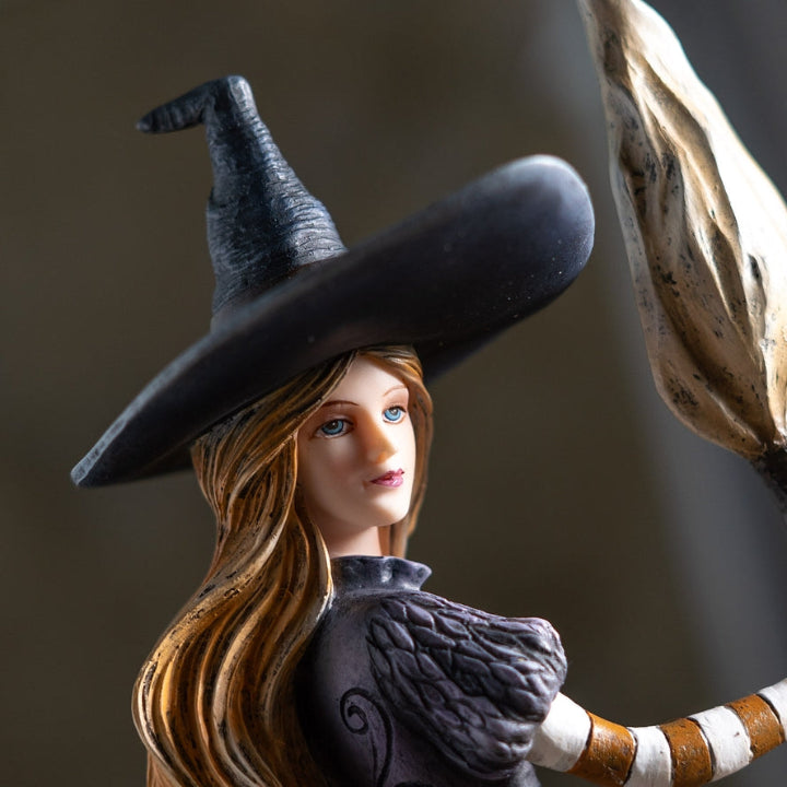 Figurine of a witch with a broomstick on a dark background