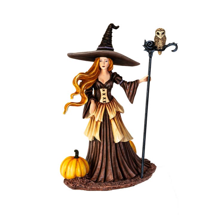 Witch figurine with a broom and pumpkin on a white background