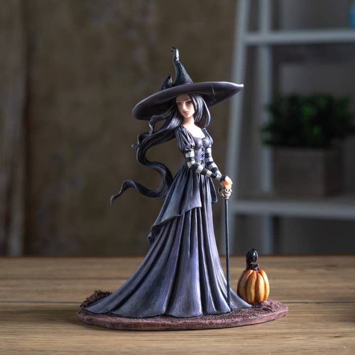 Witch figurine with a pumpkin on a wooden surface