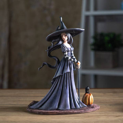 Witch figurine with a pumpkin on a wooden surface