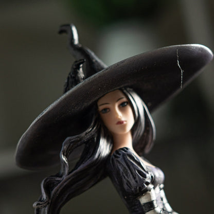 Figurine of a witch with a large black hat on a dark background