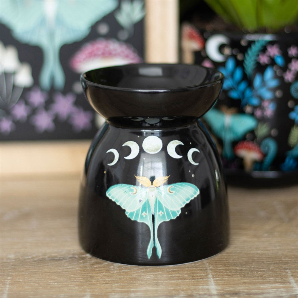 Black oil burner with butterfly design on a wooden surface