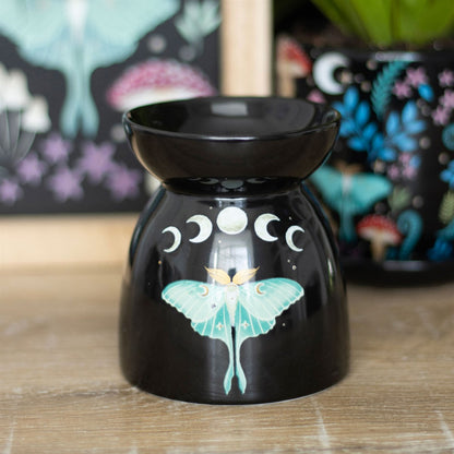 Black oil burner with butterfly design on a wooden surface