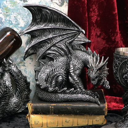 Silver dragon figurine on books with a red velvet background