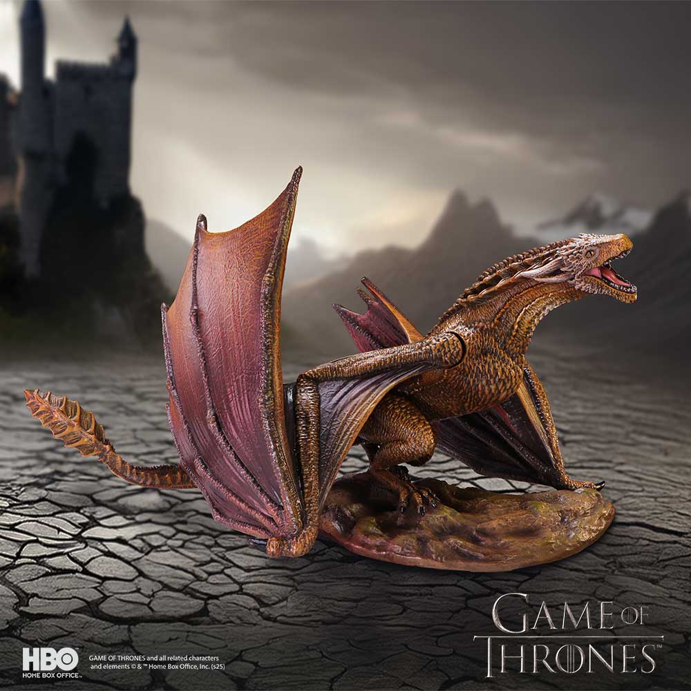 Dragon figurine from 'Game of Thrones' on a textured surface with a castle silhouette in the background.