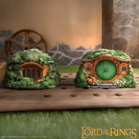Two miniature hobbit houses with green roofs on a wooden surface, inspired by 'The Lord of the Rings'.