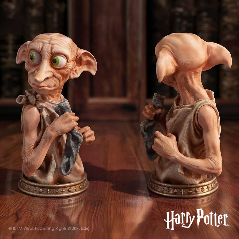 A collectible figurine of Dobby the house-elf from Harry Potter, shown from two angles on a polished wooden surface. The figurine has pale peach skin, large green eyes, and holds a gray cloth.