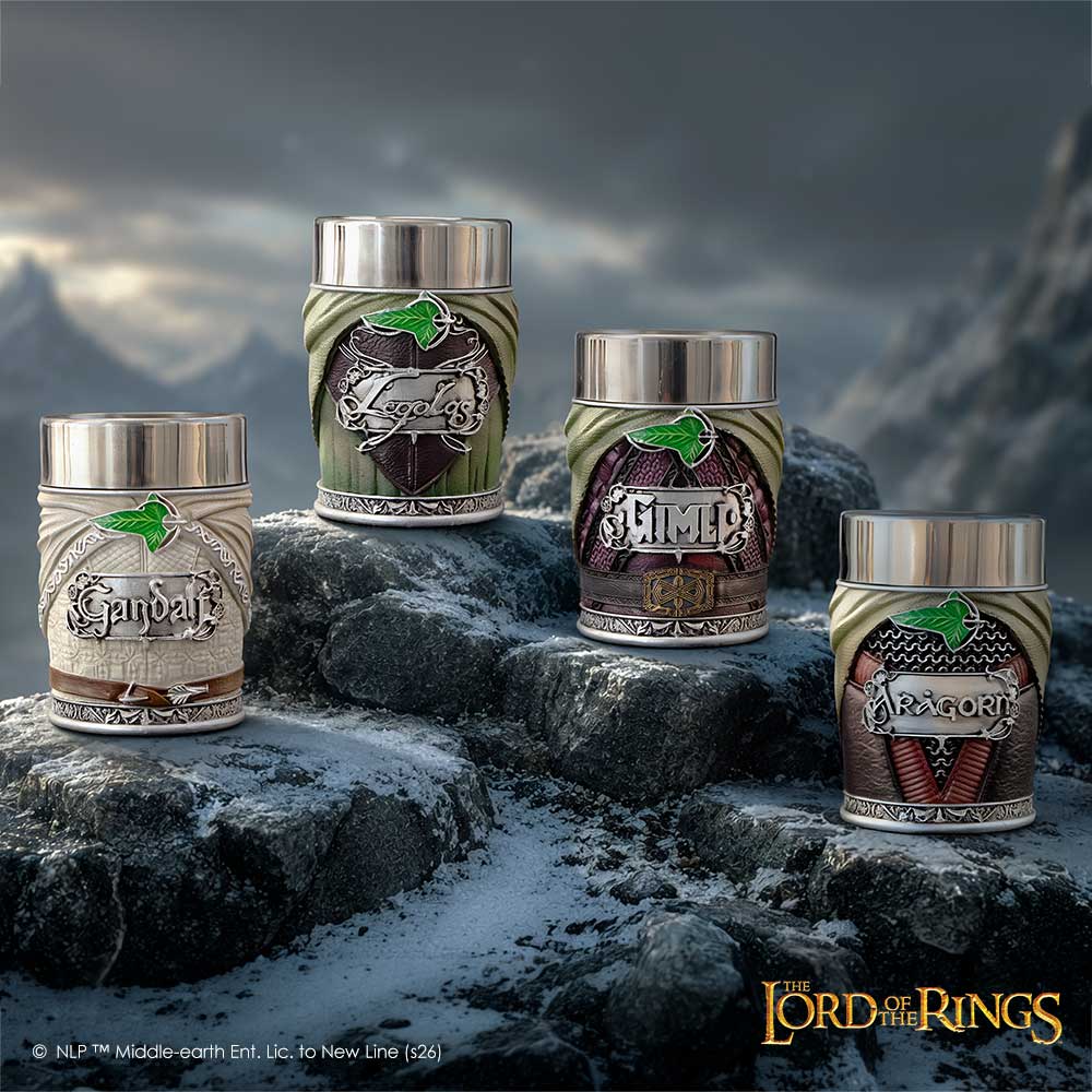 Four The Lord of the Rings themed shot glasses displayed on dark rocks against a dramatic mountain backdrop. The shot glasses feature green, brown, and beige designs with silver metal lids and detailed fantasy artwork including a green leaf, a red winged emblem, and a red-and-brown dragon motif.